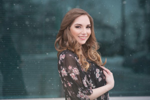 Snow falling senior picture in front of glass window