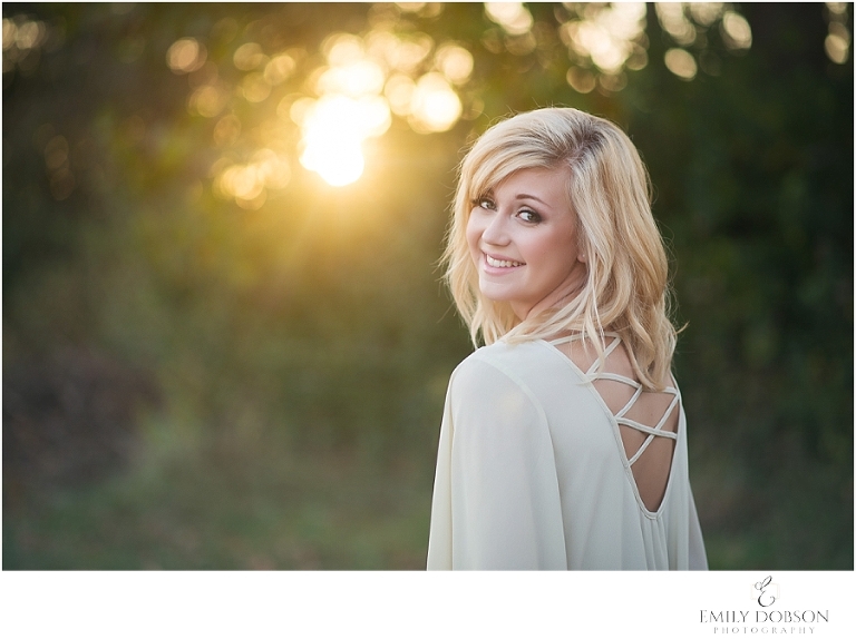 HS senior in a white dress with sun flare in the background