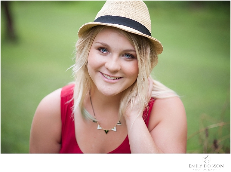 high school senior in a red dress with a hat on