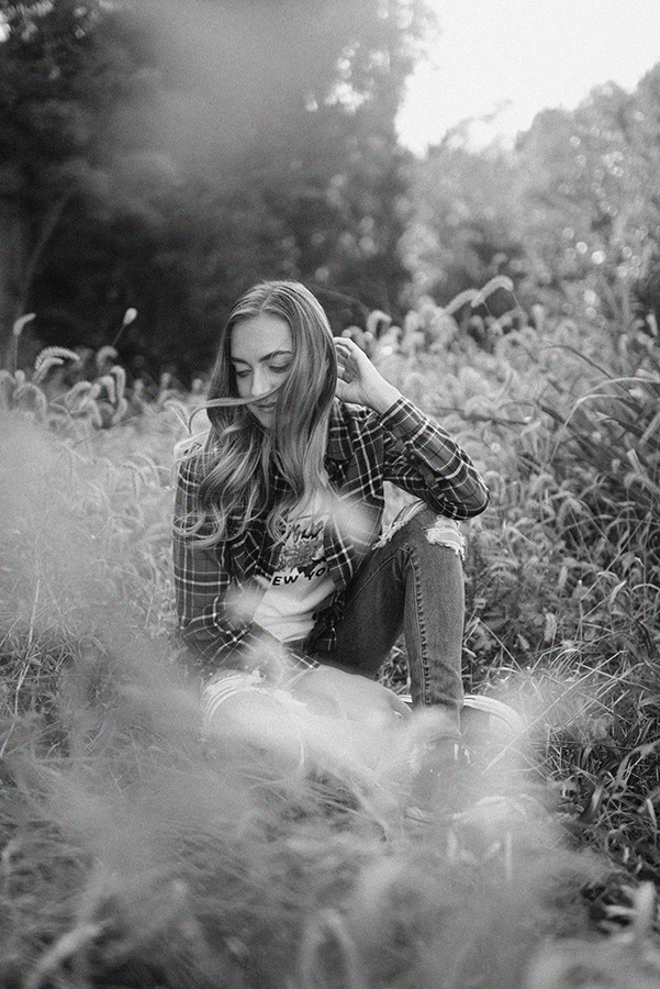 Black and white photo; high school senior and her hair is blowing in the wind