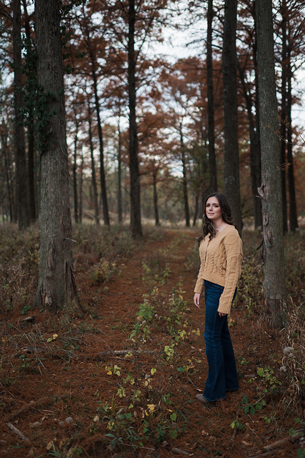 high school senior girl standing in the woods